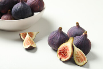 Whole and cut tasty fresh figs on white table