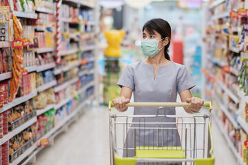 Young woman wearing protective face mask and  shopping in grocery or department store protect...