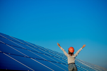 Fototapeta na wymiar Beautiful young engineer standing near solar panels outdoors, Green Energy Concept