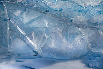 Transparent blue ice block with beautiful crystal structure on hummock background, scenic winter landscape, closeup view