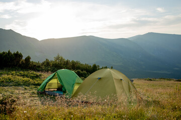 view of tourist tent in mountains at sunrise or sunset. Camping background. Adventure travel active lifestyle freedom concept. Summer vacation.