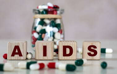 Abbreviation AIDS text on wooden cubes on a light background with a jar of pills
