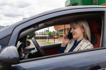Naklejka premium Happy blonde talking on the phone in the car