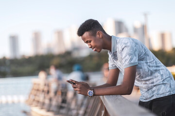 Young black man in casual clothes typing a sms with his mobile phone, copy space includes