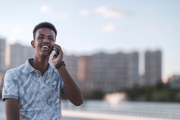 Happy young black man in casual clothes talking with mobile phone copy space includes