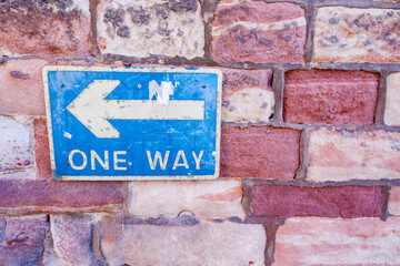 Obraz premium Brick Wall with Blue and White One Way Sign