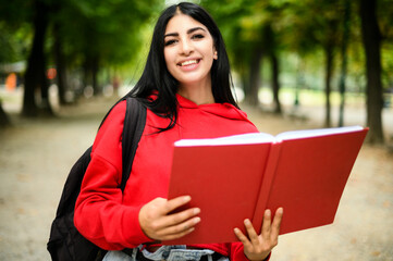Fototapeta premium Beautiful female student holding a book outdoor