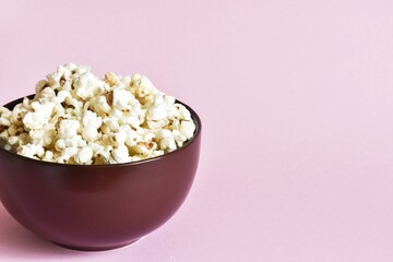 A bowl of popcorn on a pink background.
Copy space, close up.
