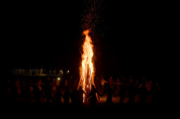 People dance at night around a big fire