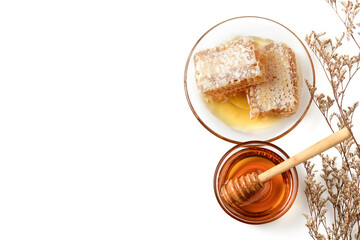 Honeycomb on dish with honey dipper and dry flower isolated on white.