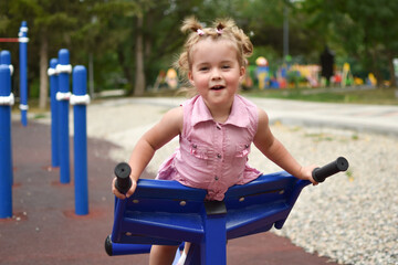 Fototapeta na wymiar Baby laughing little girl on the playground. Young cute sportswoman.