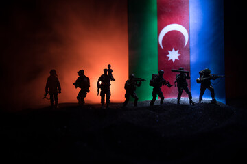 Azeri army concept. Silhouette of armed soldiers against Azerbaijani flag. Creative artwork decoration. Military silhouettes fighting scene dark toned foggy background.