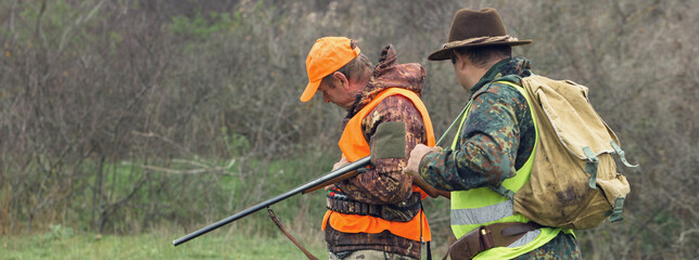Hunters man in rural field with shotgun and backpack during hunting season