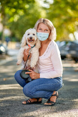 Portrait elderly woman with a dog outdoors an antivirus mask