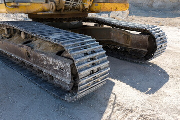 A close-up of the tracks of a heavy large excavator in a mining quarry.
