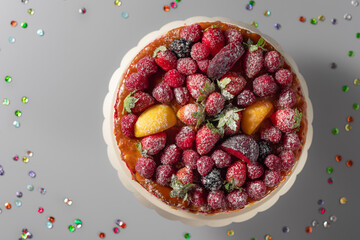 delicious red velvet cake, decorated with fresh berries and powdered sugar. Celebration concept. top view. gray background with sparkles. copy space