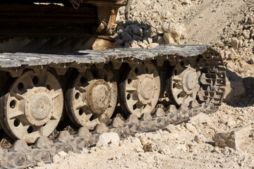 A close-up of the tracks of a heavy large excavator in a mining quarry.