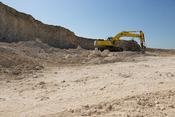 Obraz premium A large yellow tracked excavator is mining rock in a quarry.