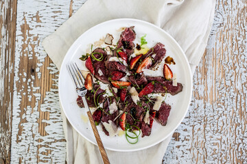 Overhead view of carpaccio and strawberries salad served on plate