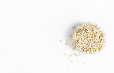 Dry oatmeal in a bowl and scattered nearby, isolated on a white background with copy space. View from above. The concept of healthy food, diet, healthy breakfast.