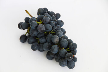 Black grapes, large fresh fruits with green leaves on a white background
