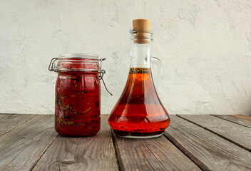dried tomatoes in a jar in oil, next to a jar of olive oil, seasoned with spices.