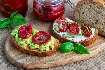 Sandwich with sun-dried tomatoes, avocado, basil, curd cheese on croutons. Vegetarian breakfast or snack