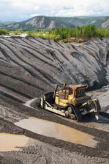 Bulldozers in mountainous wooded areas, layer by layer, remove mountain soil from the surface and shovel it to the side.