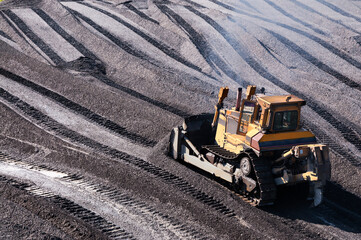 Bulldozers in mountainous wooded areas, layer by layer, remove mountain soil from the surface and shovel it to the side.