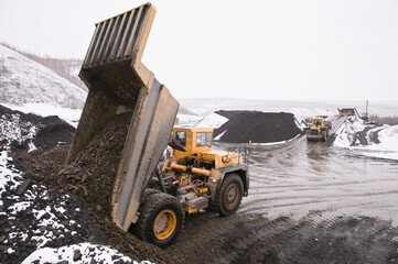 Winter.  Excavation work in the highlands at the beginning of winter. A mining dump truck unloads mountain soil © Letopisec