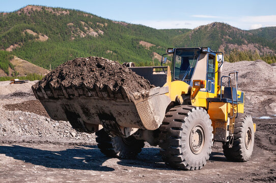 Front-end loader in the mode of transporting mountain soil. Earthworks in mountainous areas.