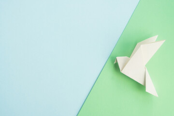 White dove bird origami on pastel background. International day of peace, hope and freedom concept. Mock up for design or greeting card. Top view, copy space