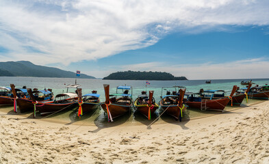Fototapeta na wymiar Traditional long tail tourist boats park in beautiful Sai Khao Beach, Ra Wi Island, Southern of Thailand