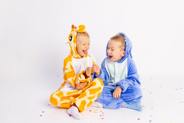 two little brother boys in bright costumes on a white isolated background eat ice cream and indulge, children's birthday, place for text