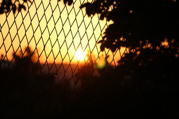 A beautiful sunset through a wired fence. 