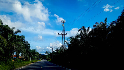 road with electric pole along the road on blue sky with the clouds background.
