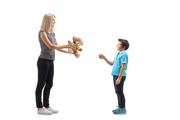Full length profile shot of a woman giving a teddy bear to a boy - Powered by Adobe