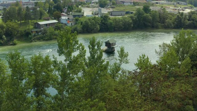 Aerial shot Serbia. Drone video of a house standing on a rock that is shrouded in a river, with a beautiful landscape background on the trees and the city.