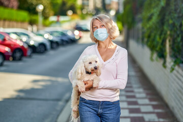 Portrait elderly woman with a dog outdoors an antivirus mask