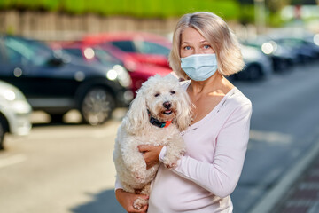 Portrait elderly woman with a dog outdoors an antivirus mask