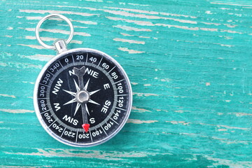Classic round compass on green wooden vintage background as symbol of tourism with compass, travel with compass and outdoor activities with compass