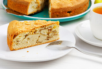 Closeup piece of apple pie with almond petals  on white wooden table. Shallow focus.