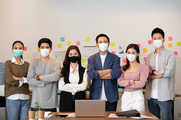 Group of Happy Asian business men leader standing wearing mask smile cross arm confidence with Business team at Co-Working space or modern office Due Covid-19 flu pandemic