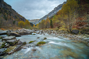 A riverbed with a mountain on the side in autumn