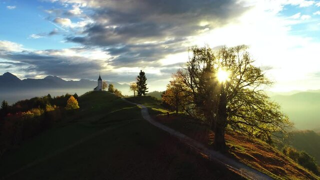 Aerial view of landscape of church of St. Primoz near Jamnik, Slovenia and Julian Alps at background 