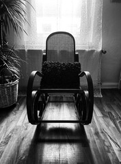 View on empty rocking chair in living room with shadow from backlight of window - grieve and loss...