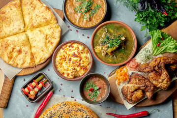 Lunch Georgian table with kharcho, lobio, tapaka chicken, khachapuri on a gray background. Top view