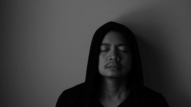 Asian men in black robes have eyes that look sad from stress, discouragement, despair or depression, black and white tones.