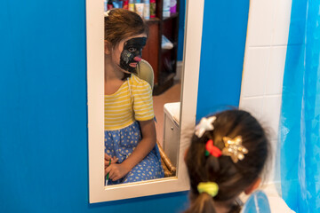 A young girl from poor deprived family is entertaining herself by face painting