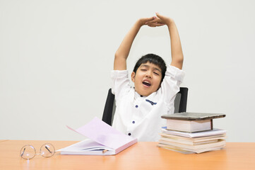 Asian boy student is showing stretch lazily while he is studying in the classroom.A young man stretch oneself during reading a book.